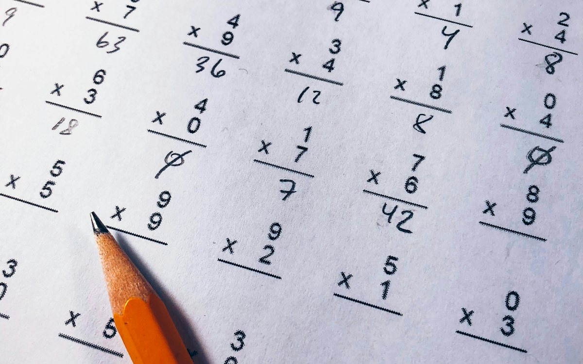 A pencil resting on a half-finished multiplication worksheet, with answers written in by hand.