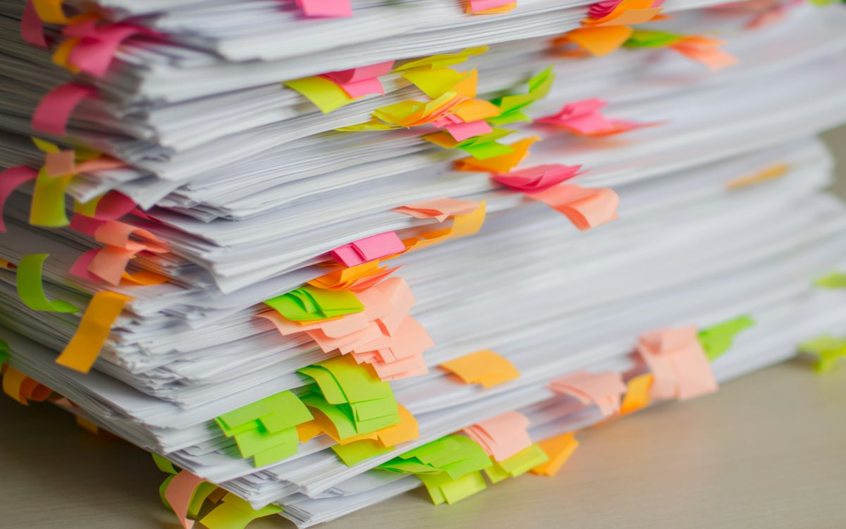 A thick stack of printed pages marked with dozens of colorful sticky page tabs.